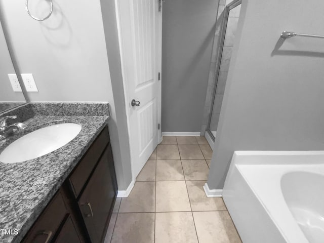 bathroom featuring a stall shower, baseboards, a garden tub, tile patterned flooring, and vanity