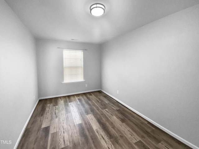 unfurnished room with dark wood-style floors and baseboards