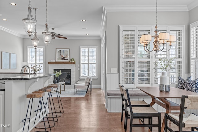 dining space featuring a brick fireplace, plenty of natural light, crown molding, and dark wood-type flooring