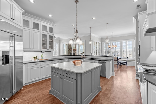 kitchen with visible vents, a kitchen island, a peninsula, stainless steel appliances, and gray cabinetry