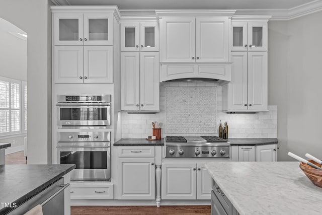 kitchen featuring appliances with stainless steel finishes, white cabinets, crown molding, and decorative backsplash