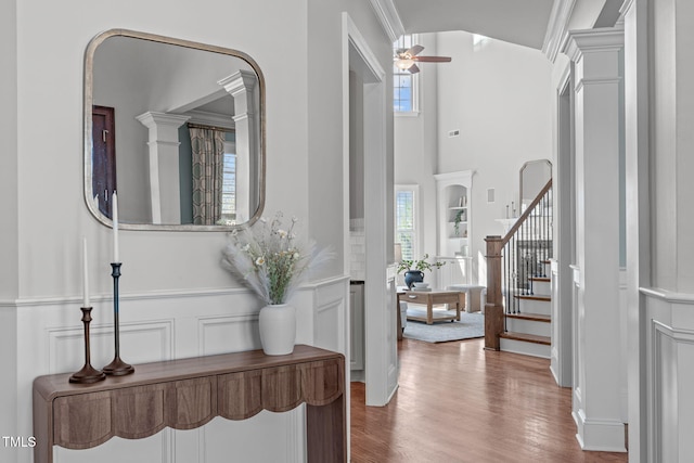 foyer with stairs, ornamental molding, a decorative wall, and wood finished floors