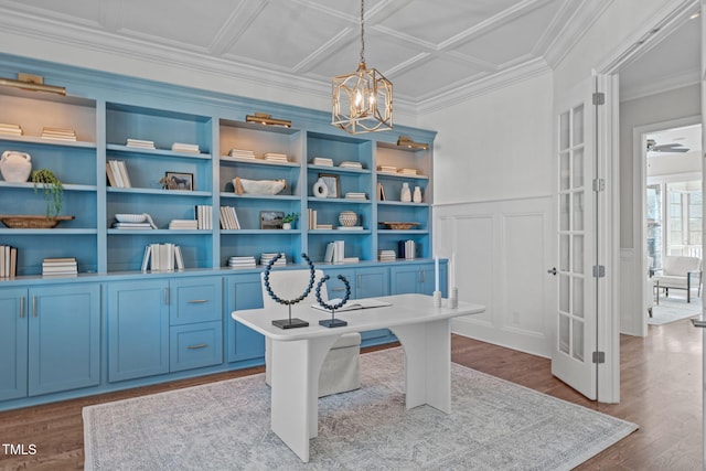 home office featuring a wainscoted wall, ornamental molding, wood finished floors, and ceiling fan with notable chandelier