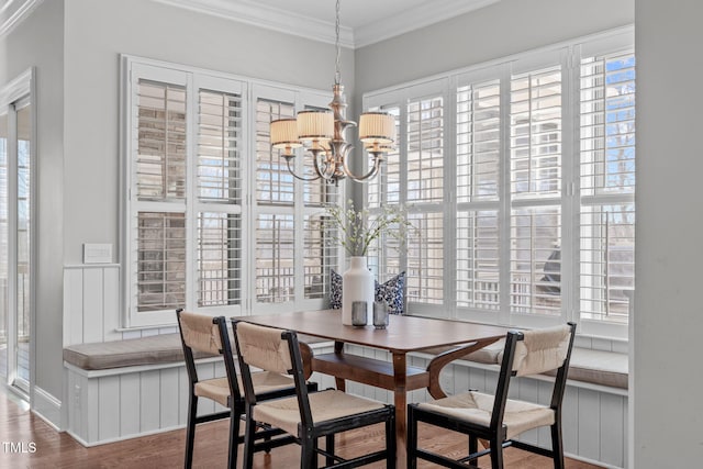 dining space featuring a chandelier, ornamental molding, and wood finished floors