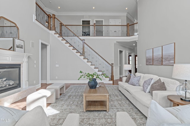 living room with ornamental molding, a high end fireplace, wood finished floors, and stairs