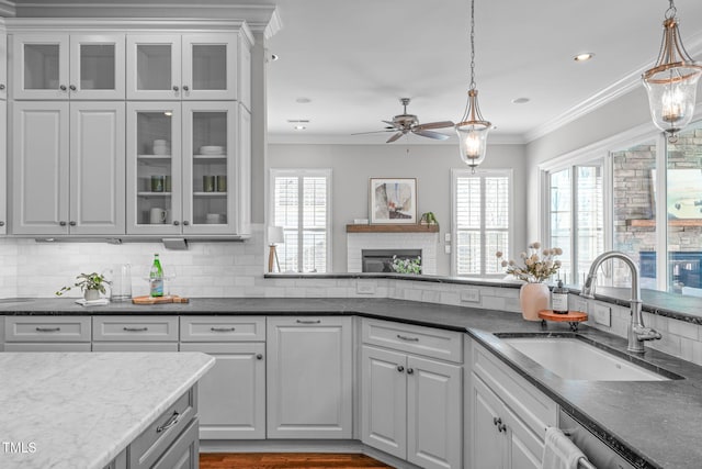 kitchen featuring stainless steel dishwasher, crown molding, decorative backsplash, and a sink