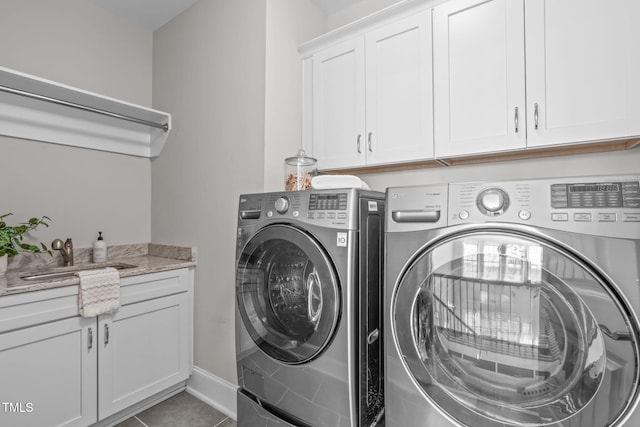 clothes washing area featuring washing machine and clothes dryer, a sink, cabinet space, and tile patterned floors