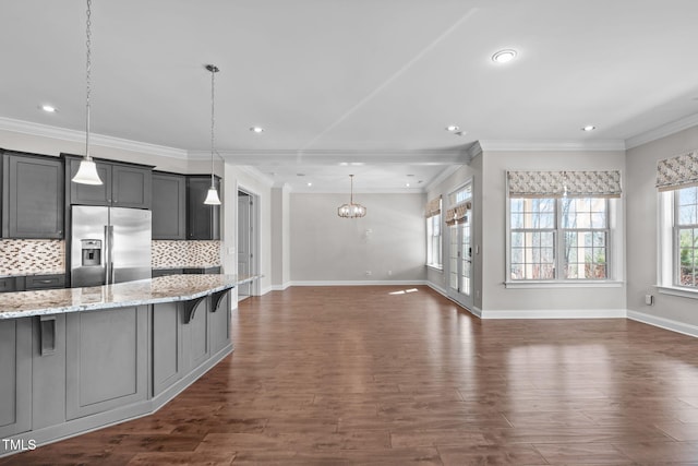 kitchen with dark wood-style floors, stainless steel refrigerator with ice dispenser, decorative backsplash, open floor plan, and a kitchen bar