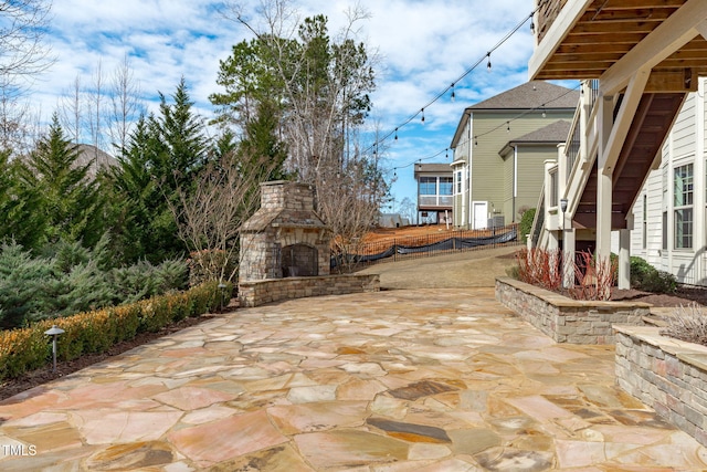 view of patio with fence and an outdoor stone fireplace