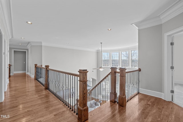 hall with crown molding, wood finished floors, and an upstairs landing