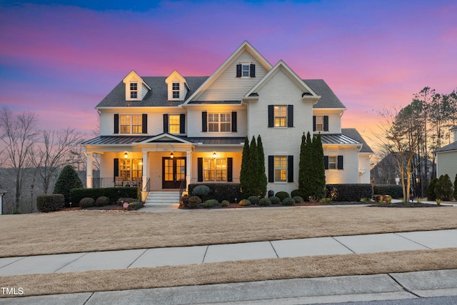 view of front of home with a standing seam roof, covered porch, metal roof, and brick siding