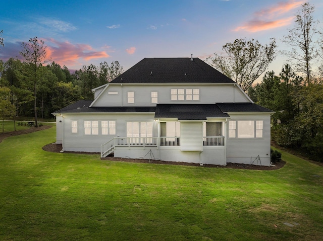 back of property at dusk with a yard