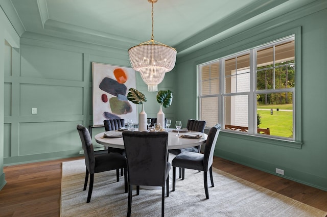 dining room featuring a chandelier, a wealth of natural light, a decorative wall, and wood finished floors