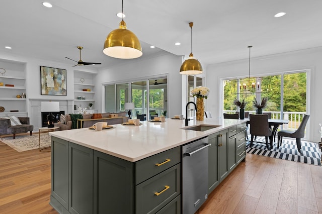 kitchen featuring light stone counters, a kitchen island with sink, a sink, hanging light fixtures, and stainless steel dishwasher