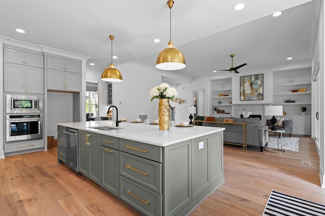 kitchen with pendant lighting, appliances with stainless steel finishes, open floor plan, a sink, and an island with sink