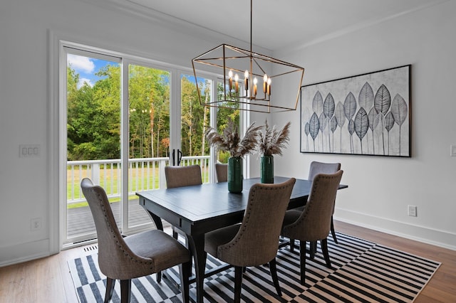 dining area with baseboards, plenty of natural light, wood finished floors, and an inviting chandelier