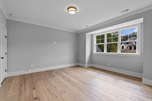 empty room featuring ornamental molding, light wood-type flooring, visible vents, and baseboards