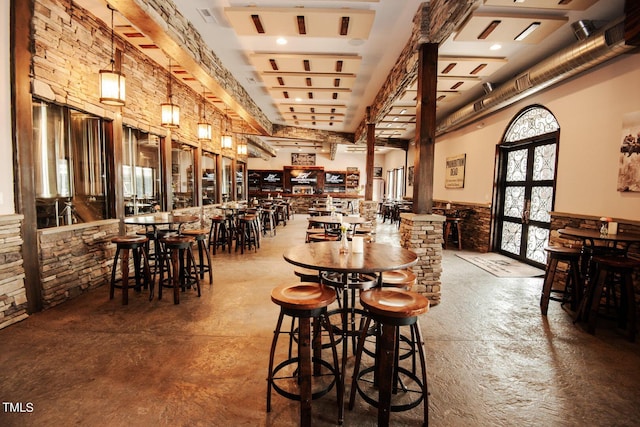 dining room featuring concrete flooring, french doors, a wainscoted wall, and a towering ceiling