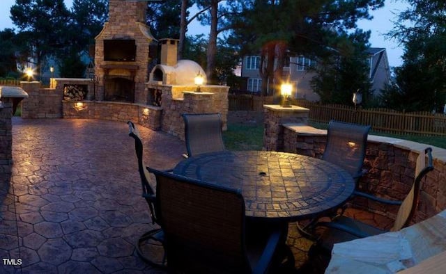 view of patio featuring fence, an outdoor stone fireplace, and outdoor dining area