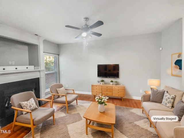 living area featuring a fireplace, wood finished floors, and baseboards