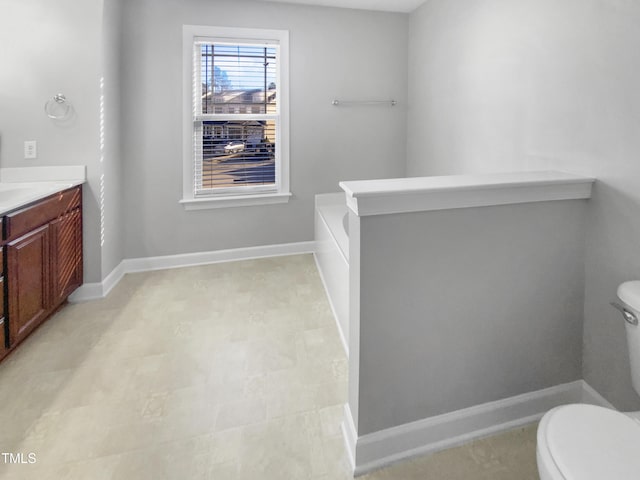 full bath featuring toilet, a bathing tub, baseboards, and vanity