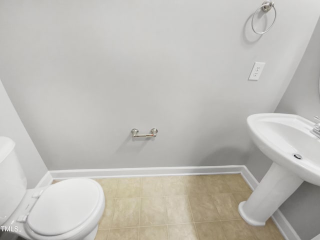 bathroom featuring toilet, tile patterned flooring, baseboards, and a sink