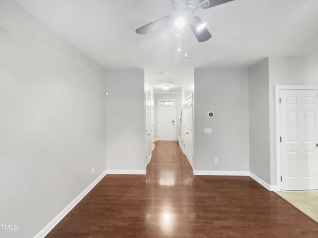 unfurnished room with ceiling fan, dark wood finished floors, and baseboards