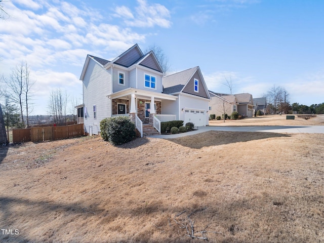 view of front of property with a porch, fence, driveway, and a garage