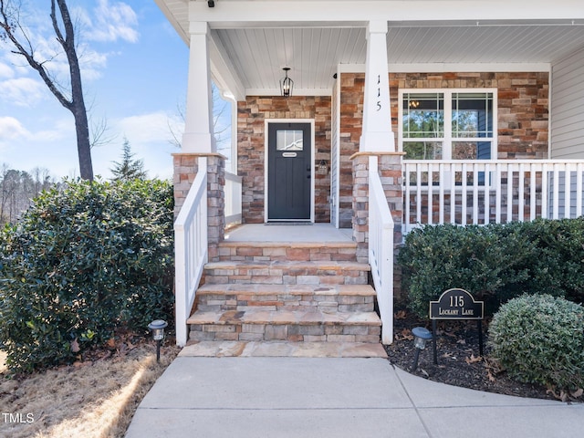 doorway to property featuring stone siding and a porch