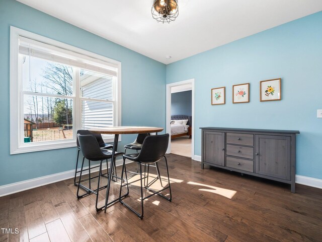 dining space with dark wood-style flooring and baseboards