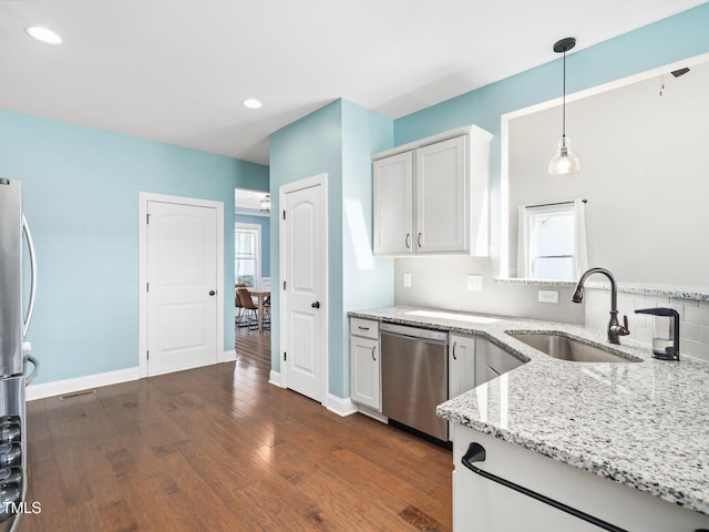 kitchen with hanging light fixtures, appliances with stainless steel finishes, a sink, and white cabinets