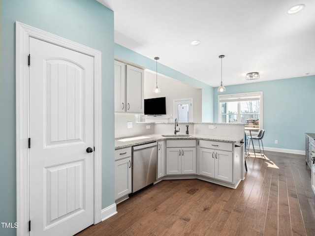 kitchen featuring hanging light fixtures, a peninsula, stainless steel dishwasher, white cabinetry, and a sink