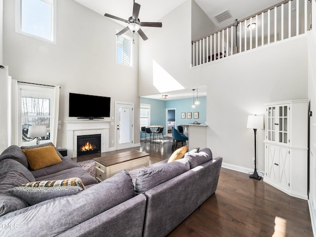 living room featuring dark wood-style flooring, plenty of natural light, and visible vents