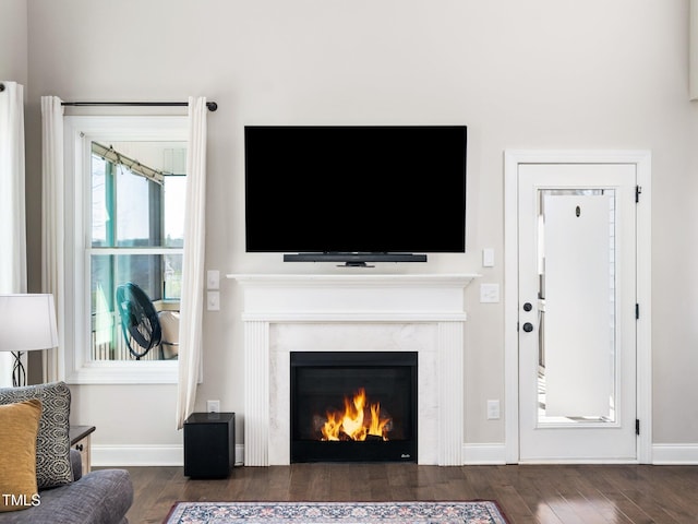 living room featuring a fireplace, baseboards, and dark wood-type flooring