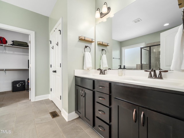 bathroom featuring double vanity, visible vents, a stall shower, a sink, and baseboards