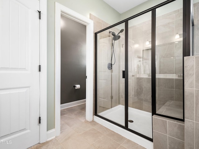 full bath with tile patterned flooring, a shower stall, and baseboards