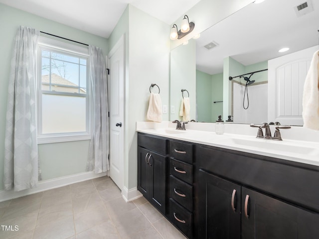 bathroom featuring tile patterned flooring, visible vents, baseboards, and double vanity