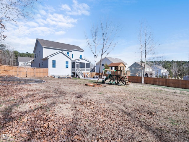 rear view of house featuring a residential view, a sunroom, a playground, and a fenced backyard