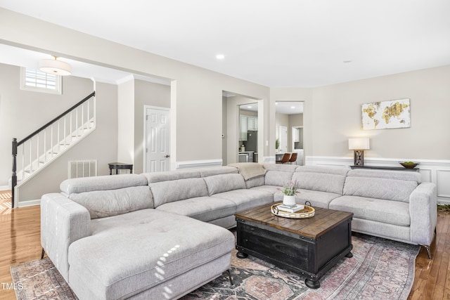 living room with a wainscoted wall, recessed lighting, visible vents, stairway, and wood finished floors