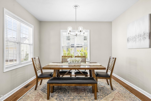 dining room with a notable chandelier, baseboards, and wood finished floors