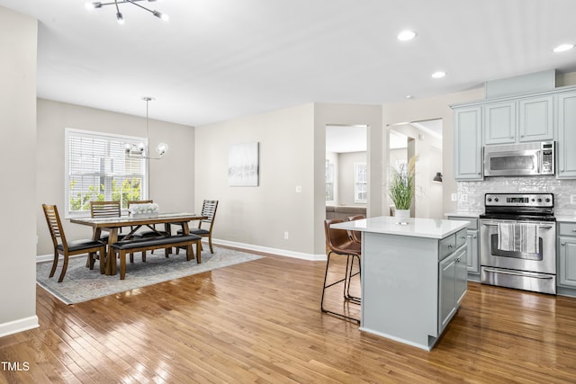 kitchen featuring a center island, stainless steel appliances, gray cabinets, light countertops, and decorative backsplash