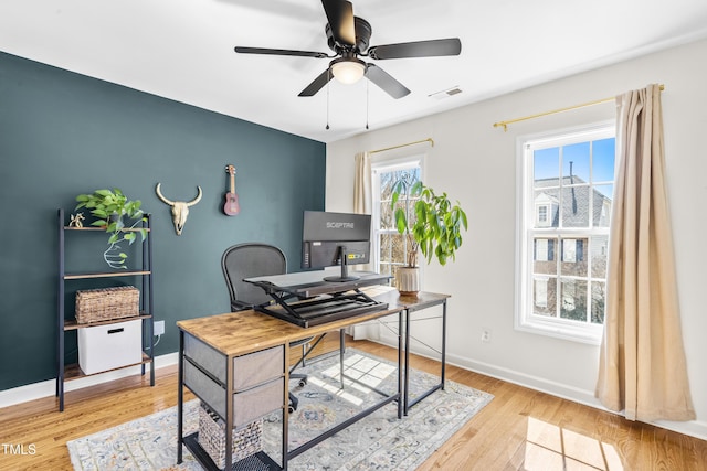 office area with light wood-style flooring, visible vents, baseboards, and ceiling fan