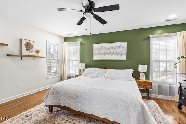 bedroom with multiple windows, light wood-style flooring, and baseboards