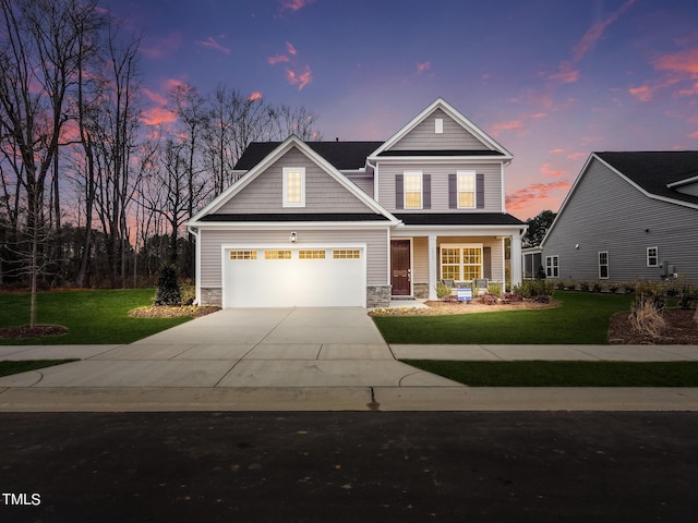 view of front of house with an attached garage, driveway, stone siding, and a front yard