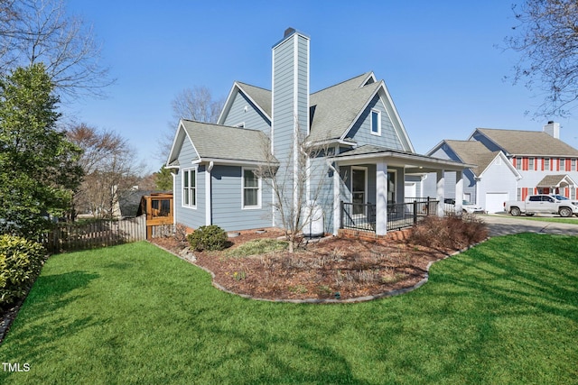 view of front of home with a shingled roof, a chimney, fence, and a front lawn