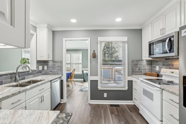 kitchen with light stone counters, stainless steel appliances, dark wood-type flooring, a sink, and white cabinetry