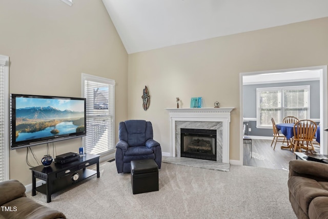 living area with high vaulted ceiling, a fireplace, a wealth of natural light, and baseboards