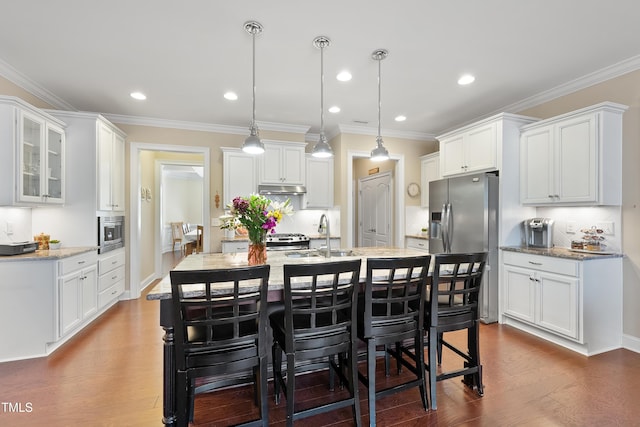 kitchen with a kitchen breakfast bar, dark wood-type flooring, stainless steel appliances, under cabinet range hood, and a sink