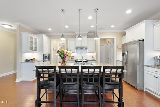 kitchen featuring a kitchen island with sink, appliances with stainless steel finishes, a breakfast bar, and dark wood-style flooring