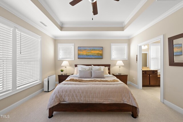 bedroom with a tray ceiling, light colored carpet, crown molding, and baseboards